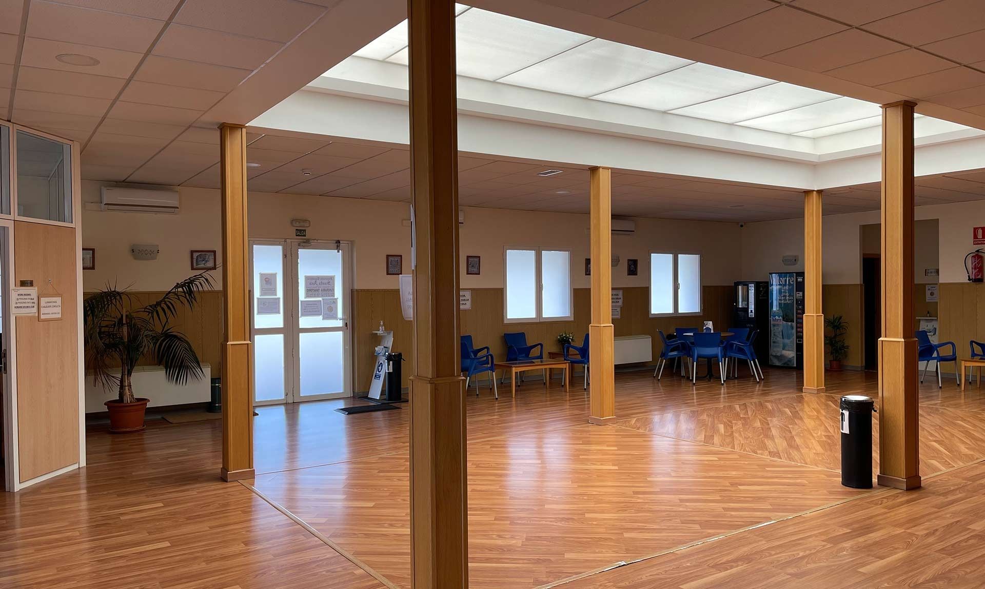 Una habitación grande con muchas ventanas y pilares de madera.