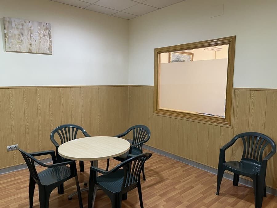 Una habitación con una mesa y sillas frente a una ventana.