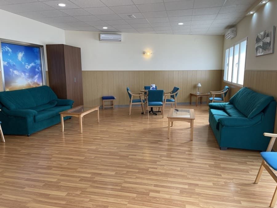 Una sala de estar con un sofá, sillas, mesas y un cuadro en la pared.