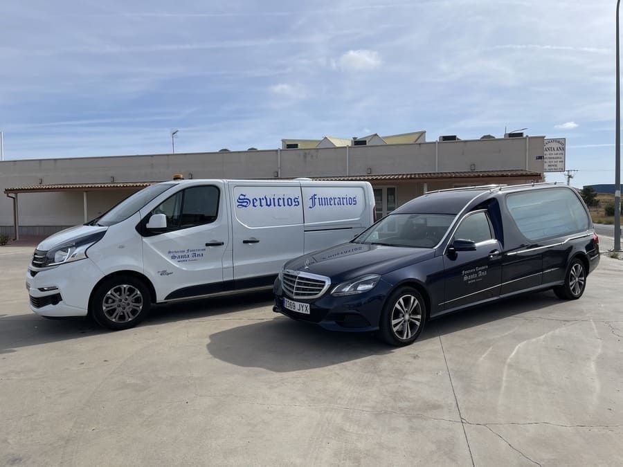 Dos coches fúnebres están estacionados uno al lado del otro en un estacionamiento.