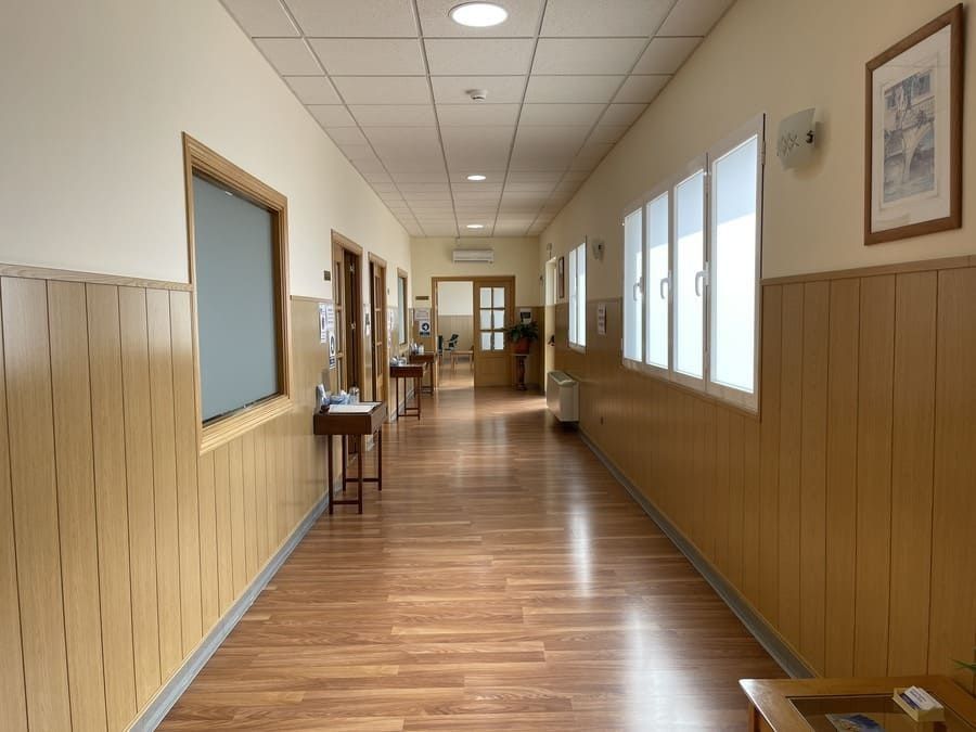 Un largo pasillo con paneles de madera y muchas ventanas.