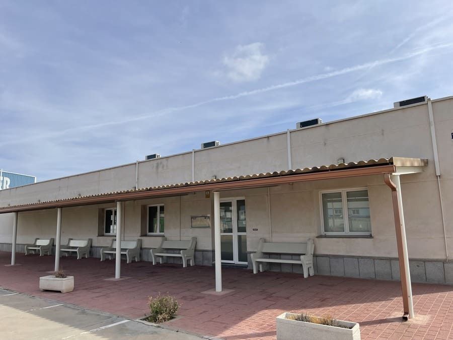 Un edificio blanco con un porche cubierto y bancos delante de él.