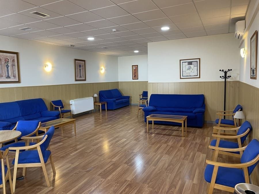 Una sala de estar con sofás, sillas y mesas azules.