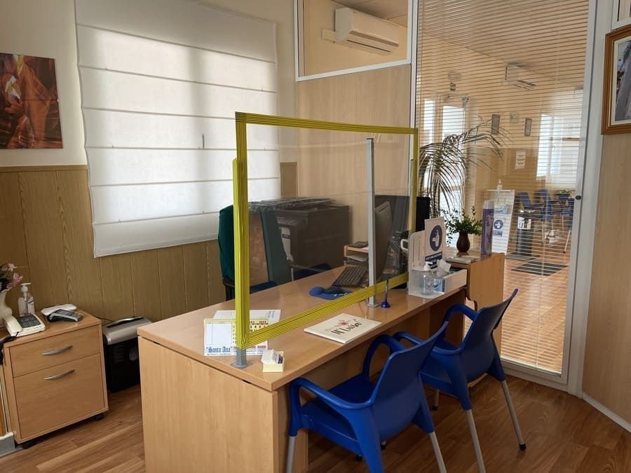 Una habitación con un escritorio, sillas y un divisor amarillo.