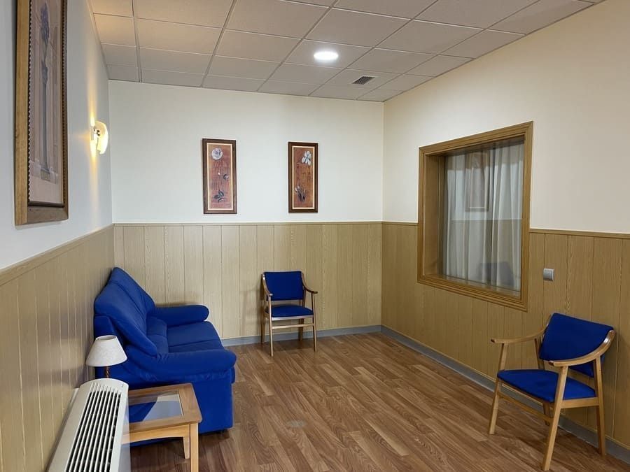 Una sala de espera con un sofá azul y sillas azules.