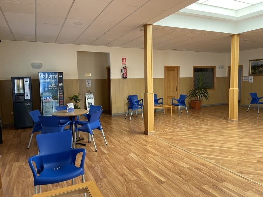 Una gran sala con mesas y sillas y una máquina expendedora.