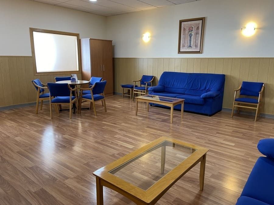 Una sala de estar con un sofá, una mesa, sillas y un espejo.