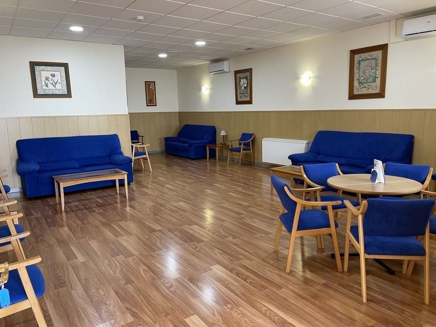 Una sala de estar con sofás azules, sillas, mesas y piso de madera.