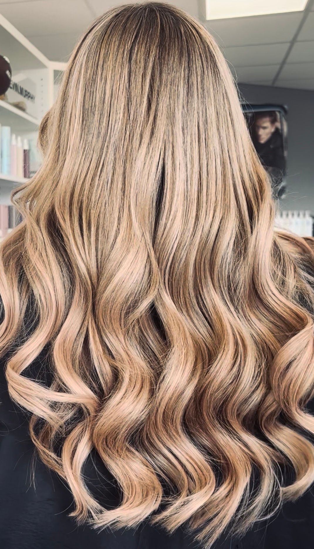 Langes, gewelltes, honigblondes, gesträhntes Haar mit lockeren Locken, von hinten gezeigt.