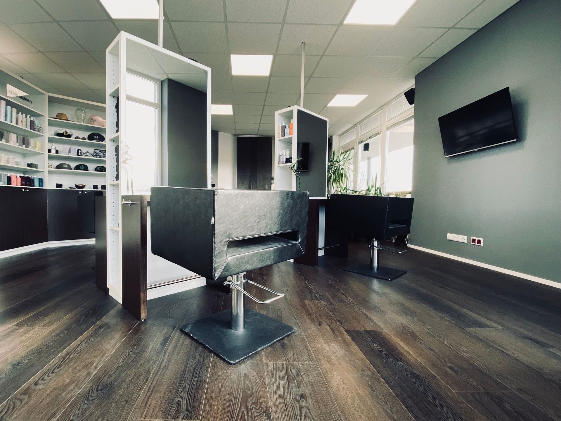 Ein Friseursalon mit zwei Stühlen und einem Fernseher an der Wand.