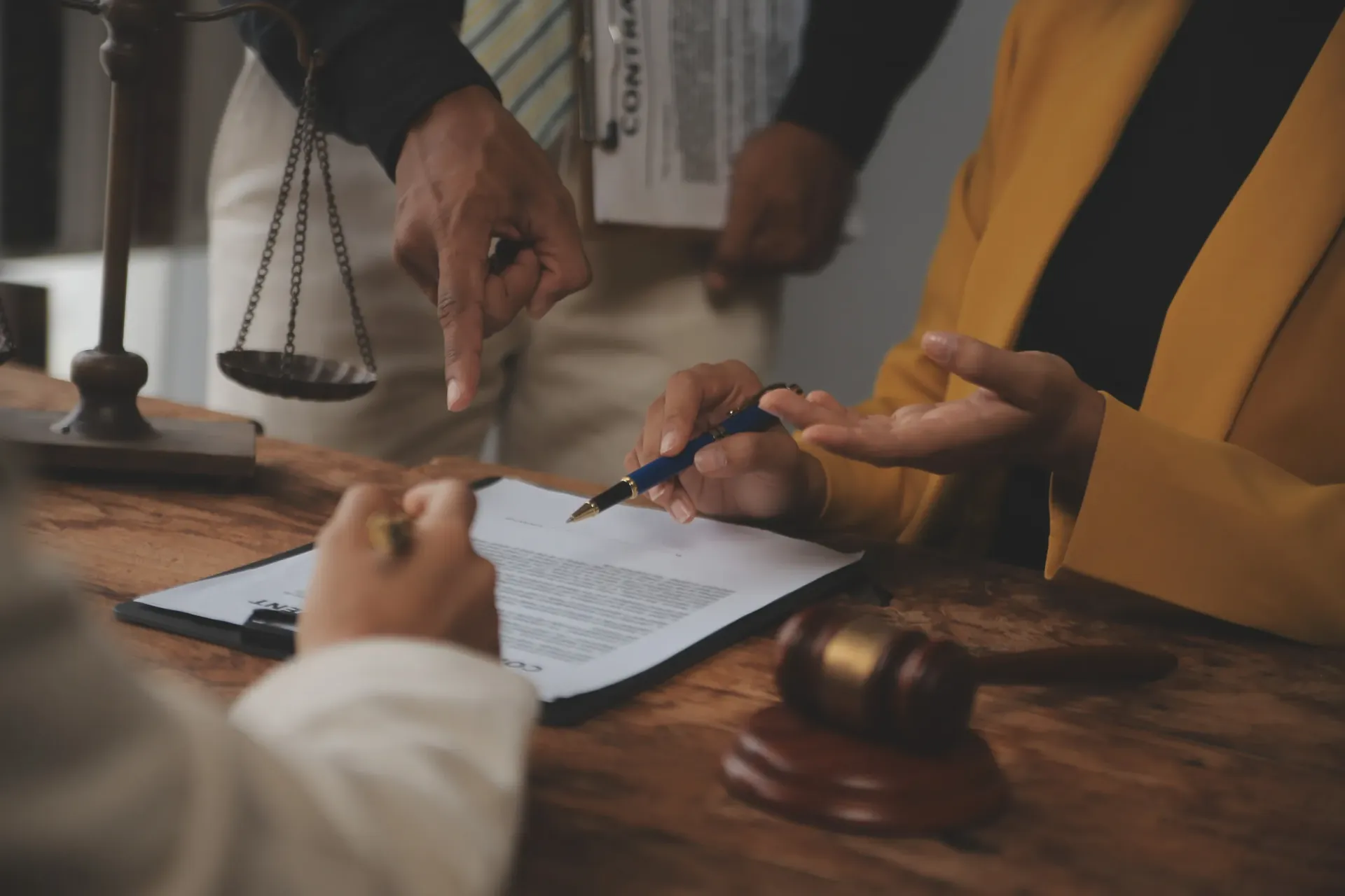 Un abogado revisa documentos en un escritorio de madera con un mazo y una balanza de la justicia cerca.