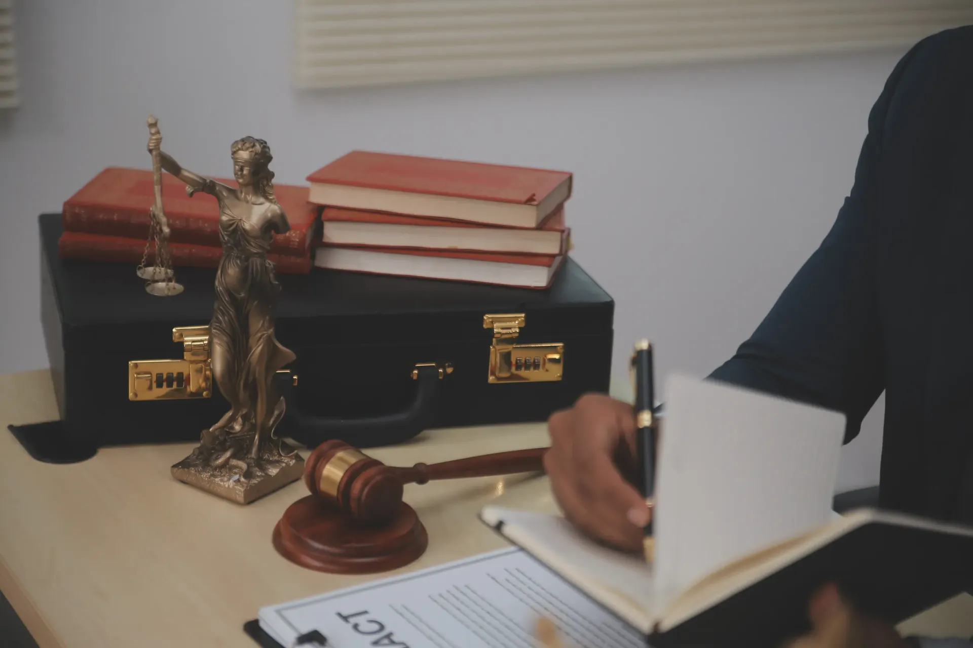 Abogado escribiendo en un escritorio con libros de derecho, reglas y un mazo.