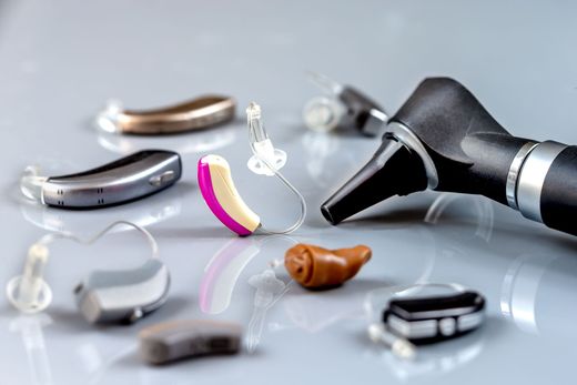 Composants et embouts d'appareil auditif disposés sur une surface réfléchissante, avec un moule auriculaire et une coque.