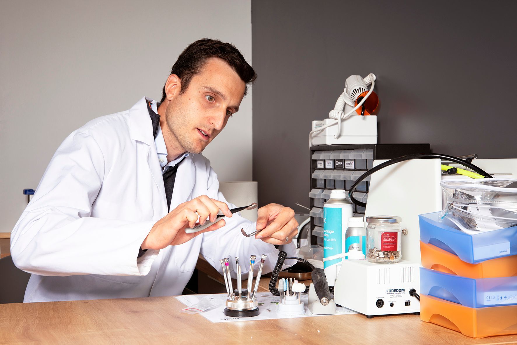 Un scientifique en blouse travaille à une paillasse de laboratoire avec de la verrerie et du matériel.