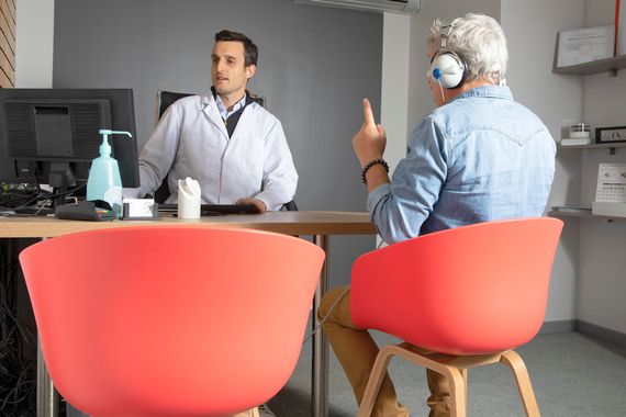 Deux personnes discutent à un bureau, avec des chaises au premier plan.