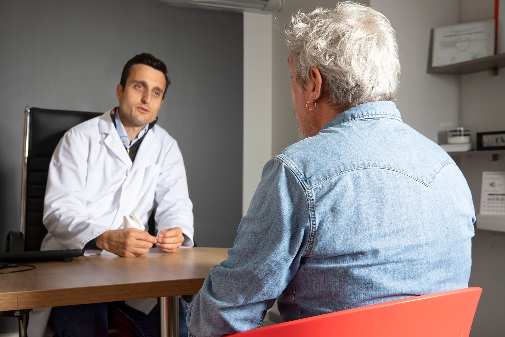 Un médecin s'entretient avec un patient assis dans un cabinet médical.