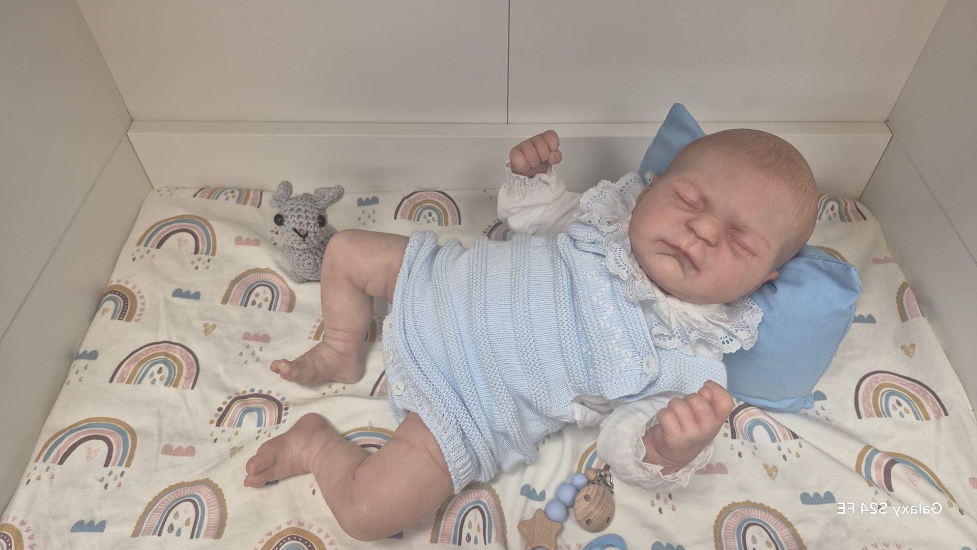 Bebé durmiendo con un conjunto azul sobre una manta estampada en una cuna.