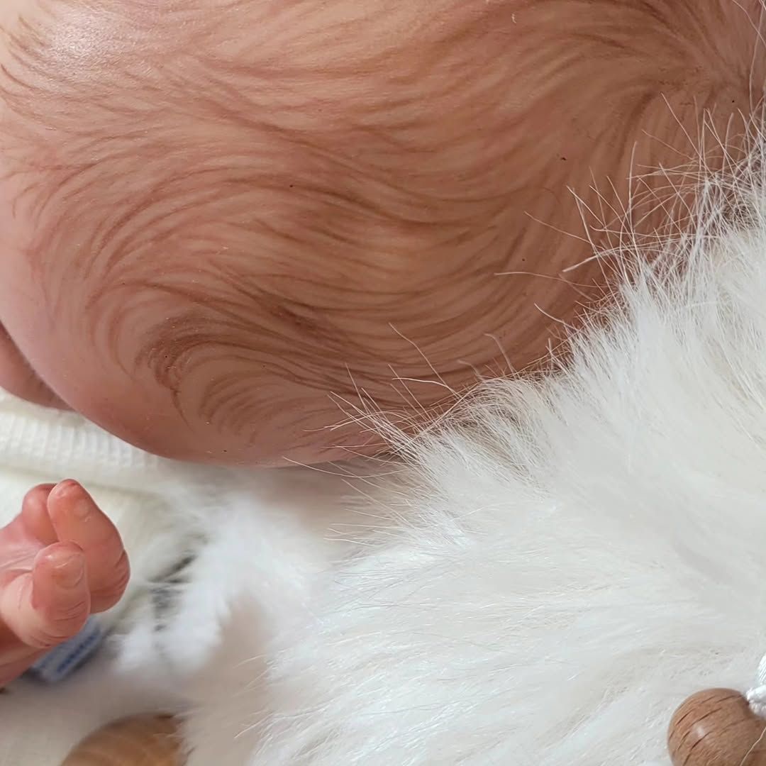 Primer plano de un bebé durmiendo sobre una manta blanca y suave.