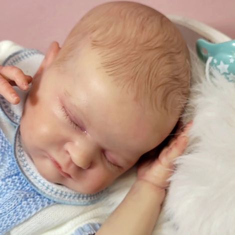 Bebé durmiendo con los ojos cerrados, descansando sobre una suave manta con un conjunto azul.