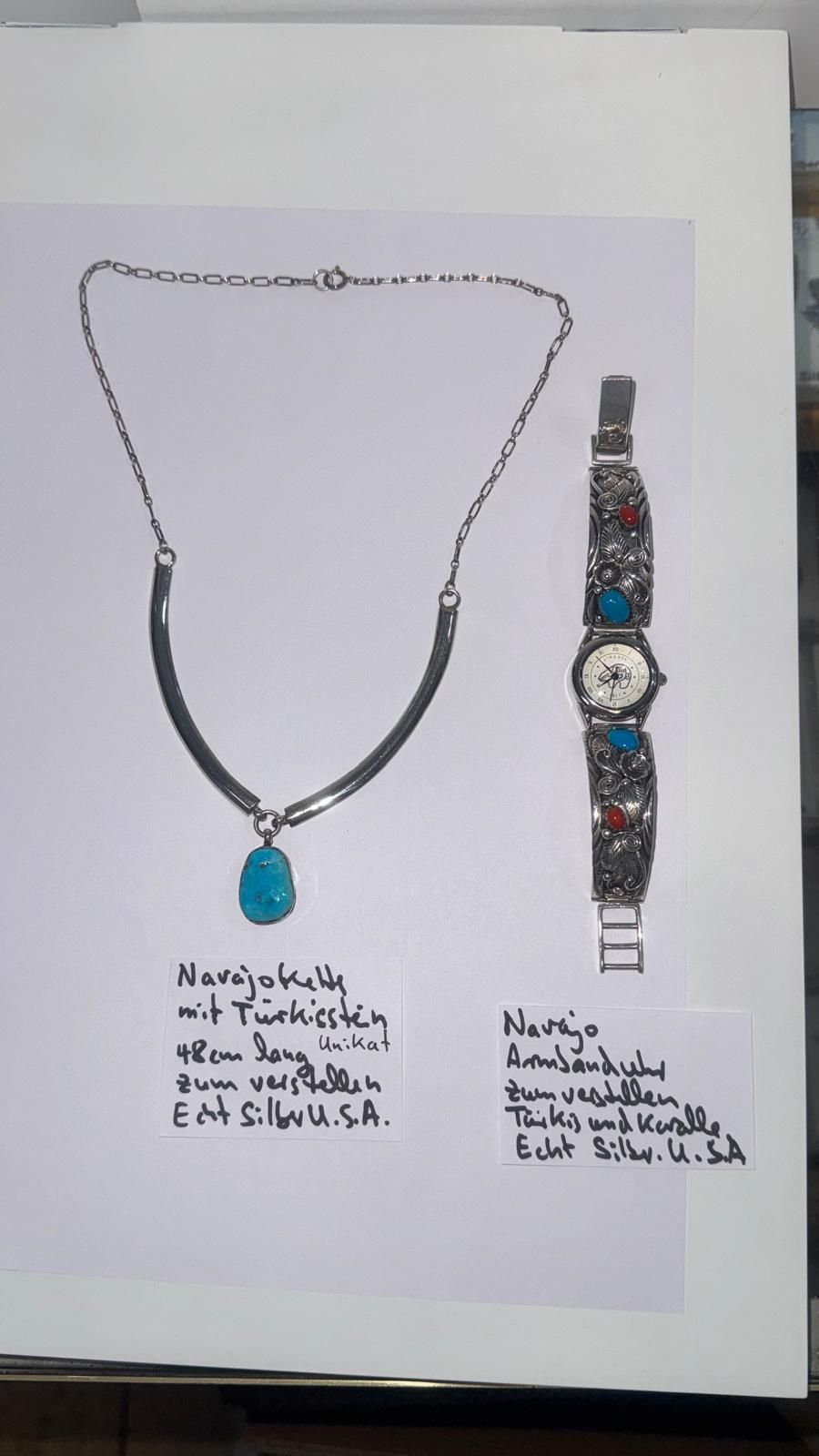 Eine Halskette mit schwarzen, blauen und gemusterten Perlen und einem Magnetverschluss, die auf weißem Hintergrund kreisförmig angeordnet sind.