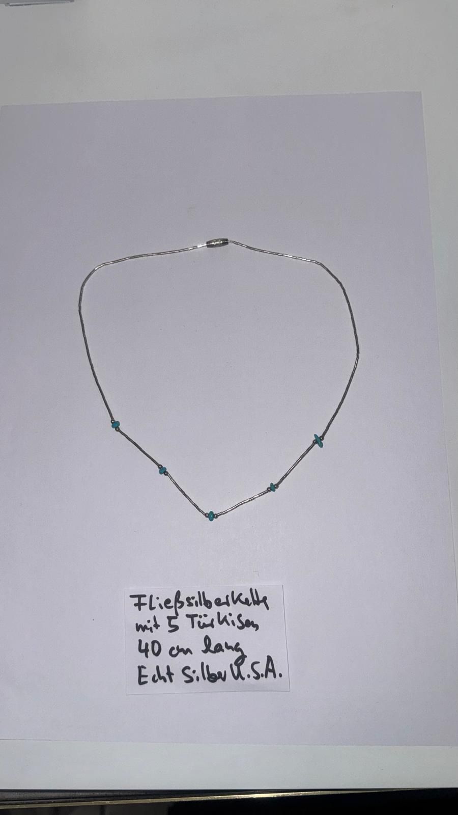 Halskette aus hellgrünen, dunkelgrünen und metallisch grauen Perlen mit Magnetverschluss und einer Notiz mit Materialangaben in deutscher Sprache.