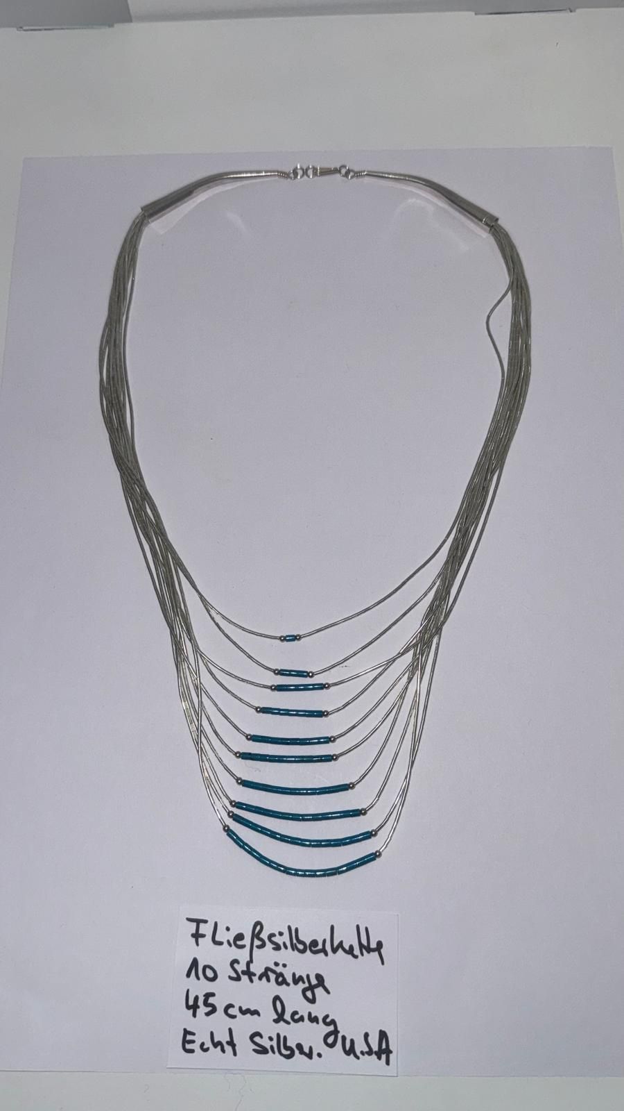 Eine Halskette aus großen, gemusterten Jaspissteinen, die durch schwarze Perlen und silberne Zwischenstücke getrennt sind, mit einem Magnetverschluss.