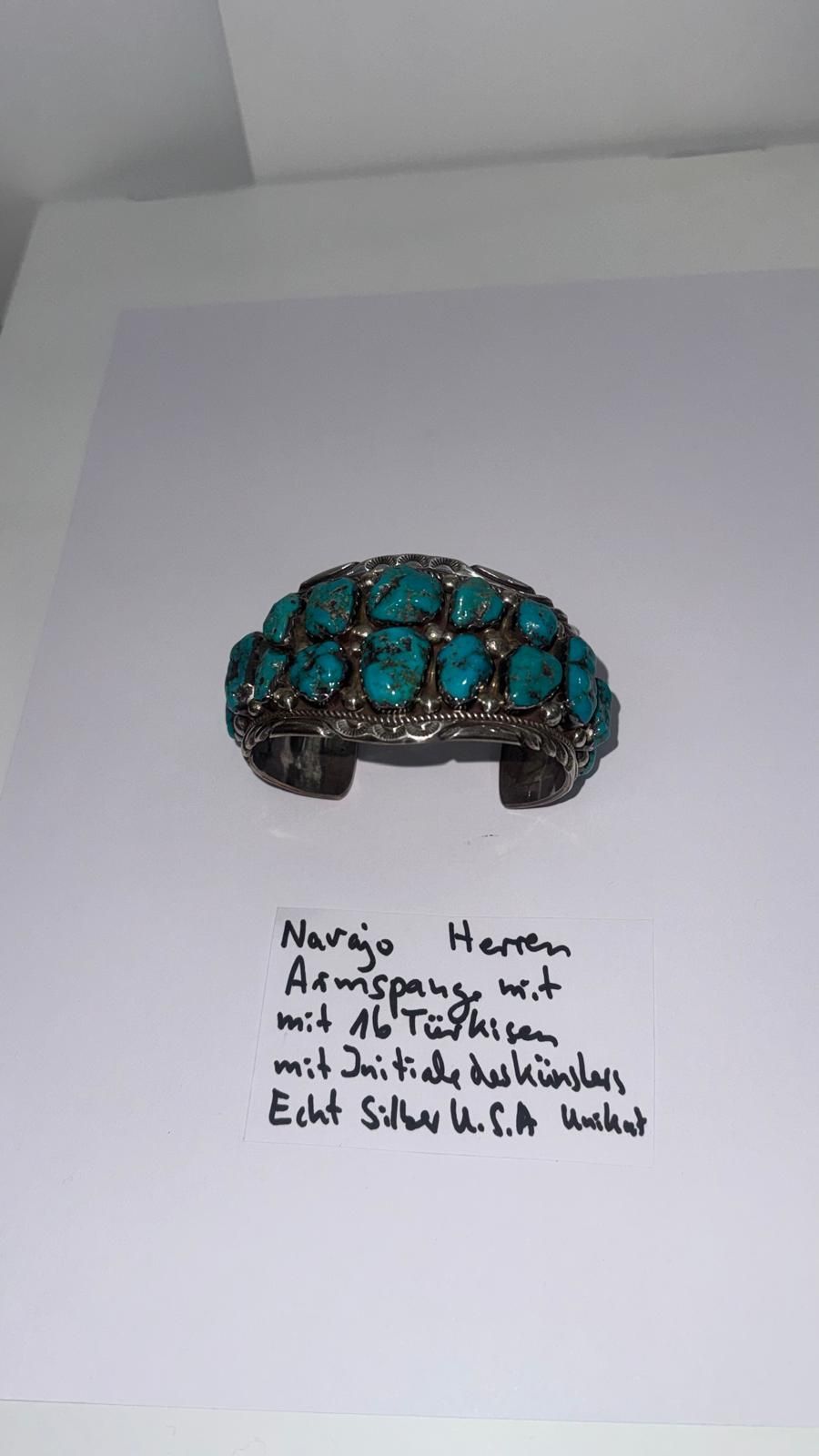 Mehrere Anhänger aus rohem Bernstein an schwarzen Kordeln mit einem handgeschriebenen Preisschild auf weißem Hintergrund.