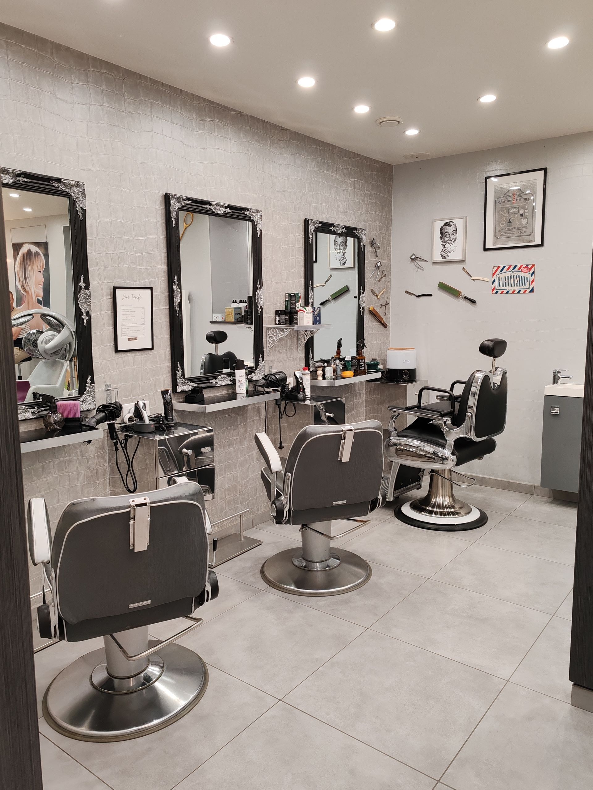 Vue intérieure d'un salon de coiffure avec trois fauteuils de barbier, des miroirs.