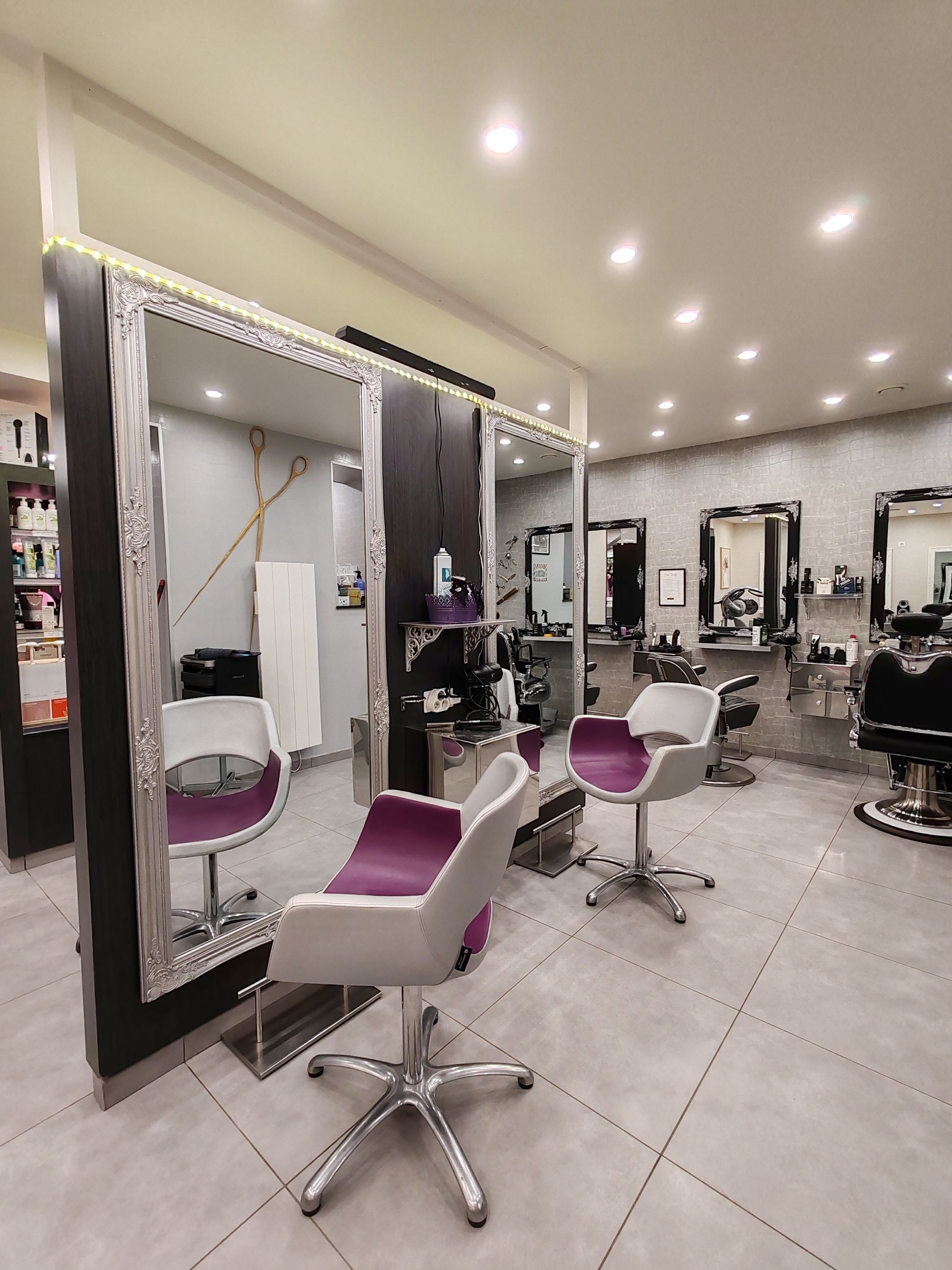 Intérieur de salon de coiffure avec miroirs, chaises et postes de coiffure.