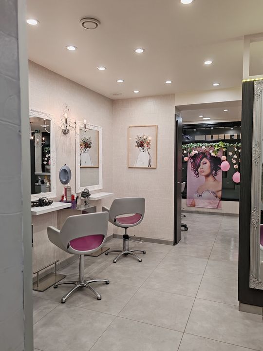 Salon de coiffure : on se fait couper les cheveux. Lumières vives, murs blancs, sol carrelé.