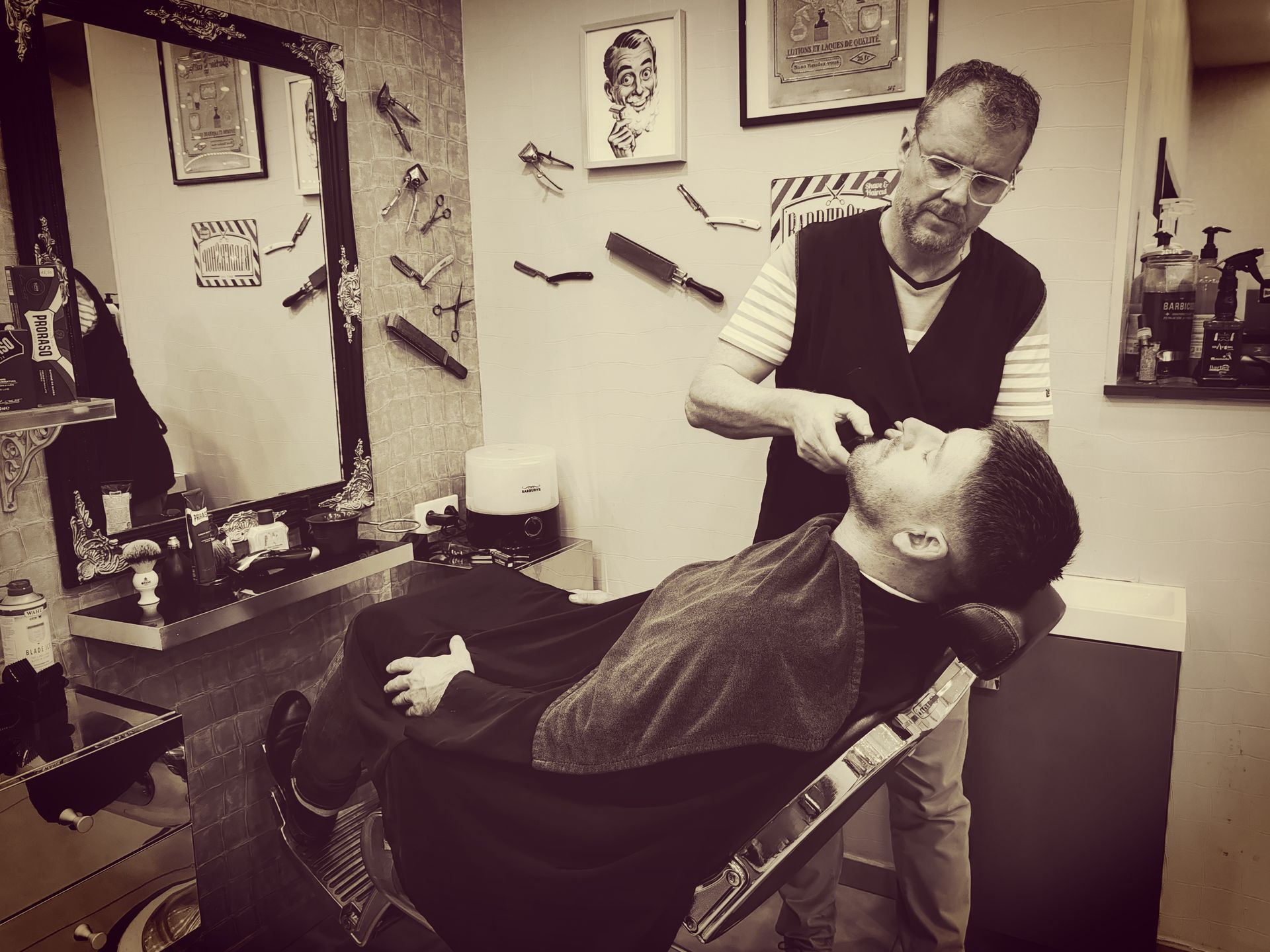 Un jeune-homme allongé sur une chaise longue se faisant raser la barbe