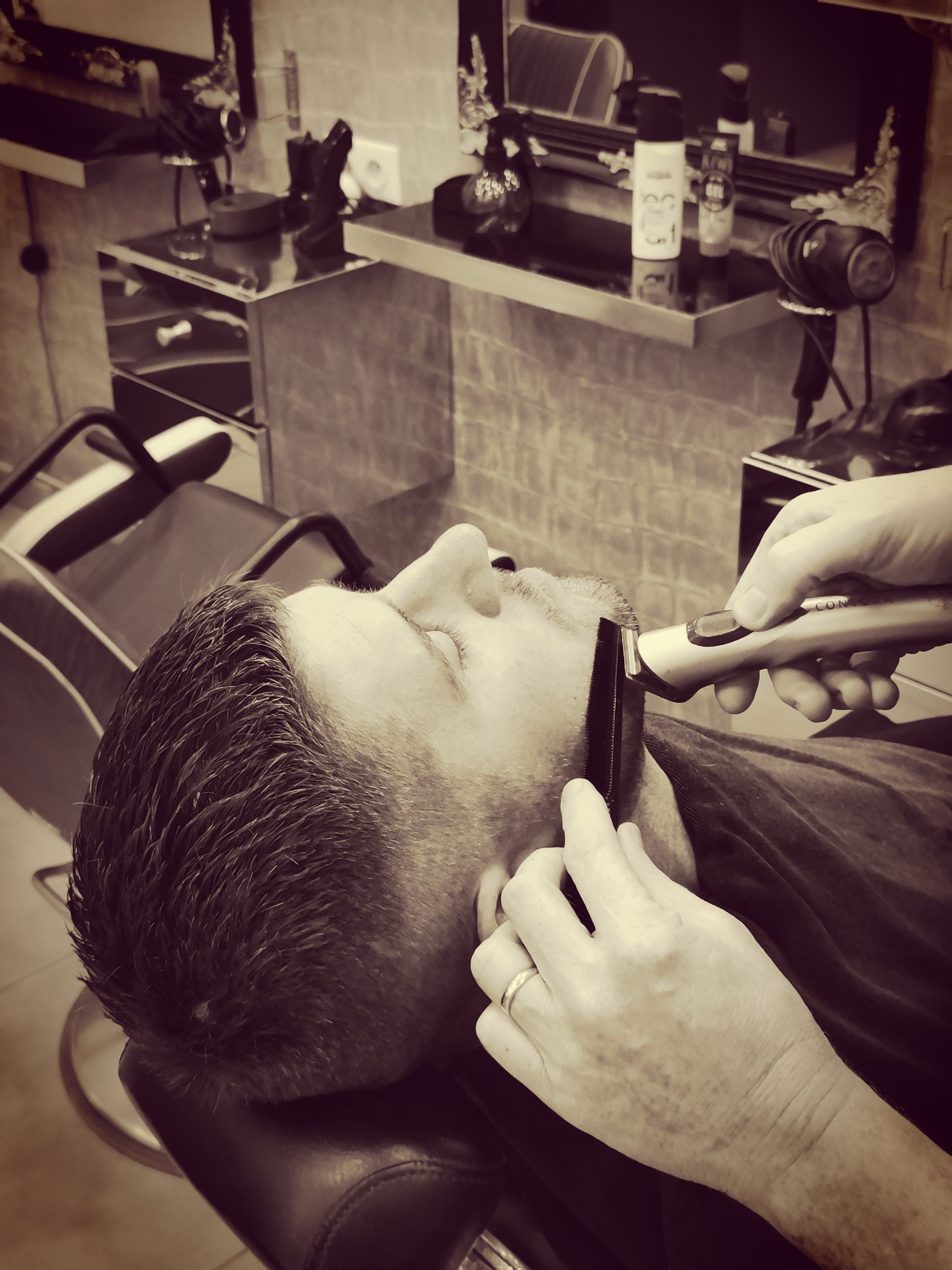 Un barbier rase un homme grâce à un rasoir