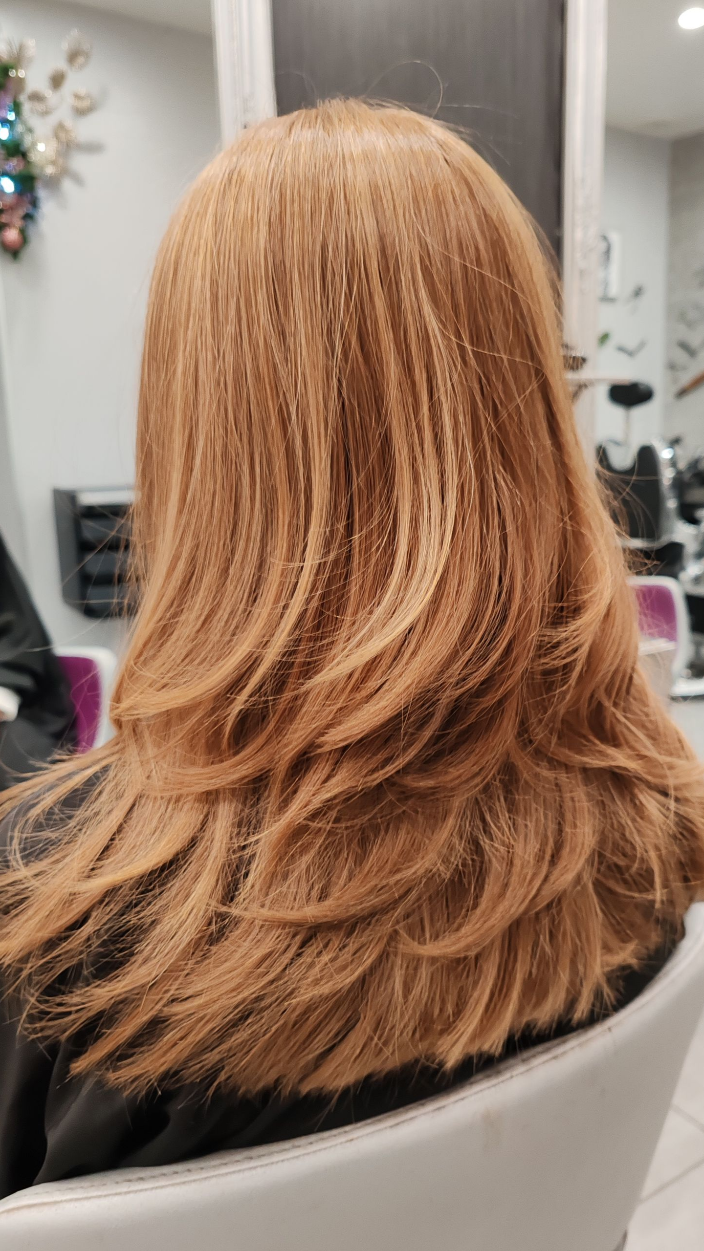 Femme aux cheveux oranges dégradés, vue de dos, dans un salon