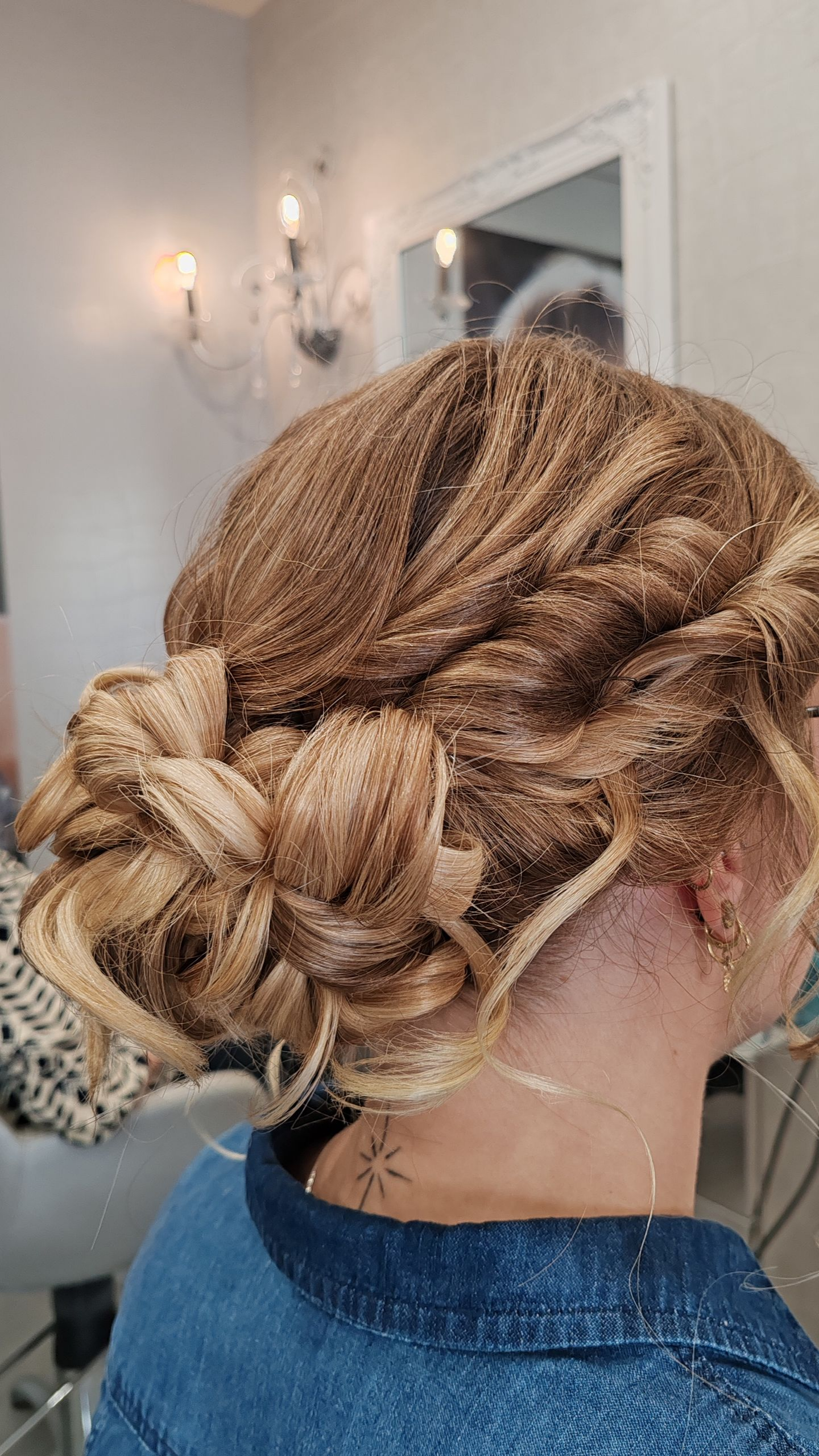 Femme avec un chignon blond dans un salon, portant une chemise en jean.