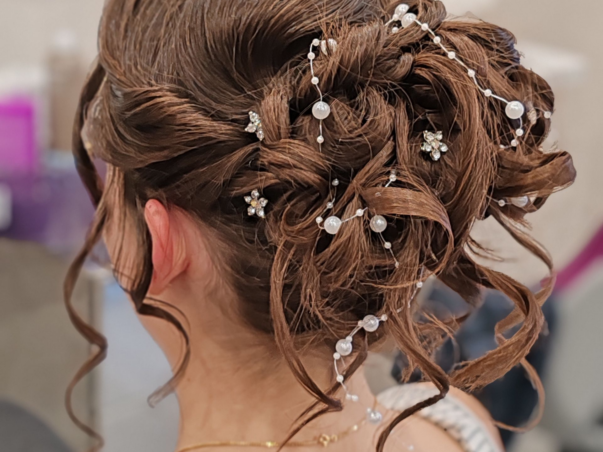 Coiffure chignon élégante avec des accents de perles et de strass.