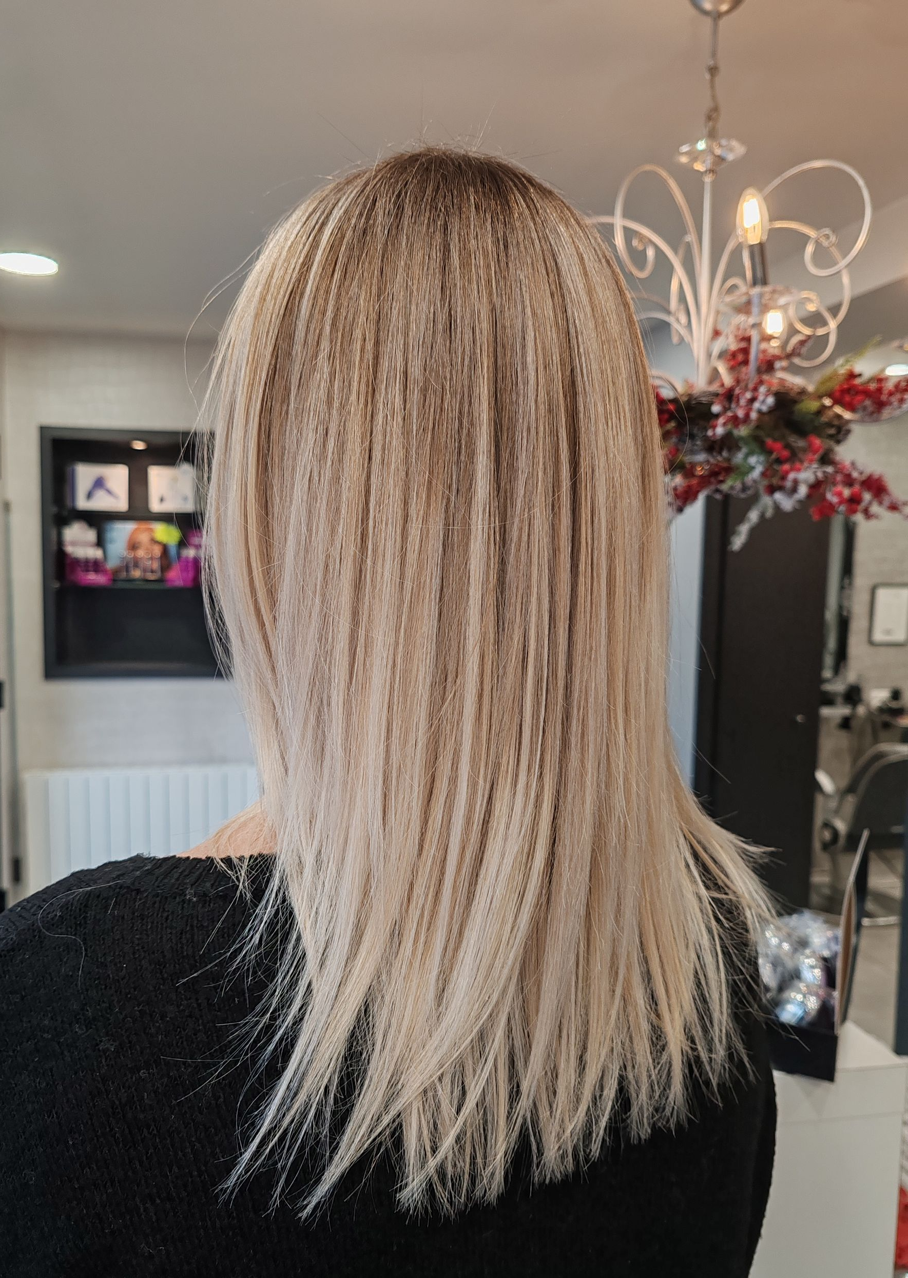 Cheveux blonds méchés lissés, dans un décor de salon.