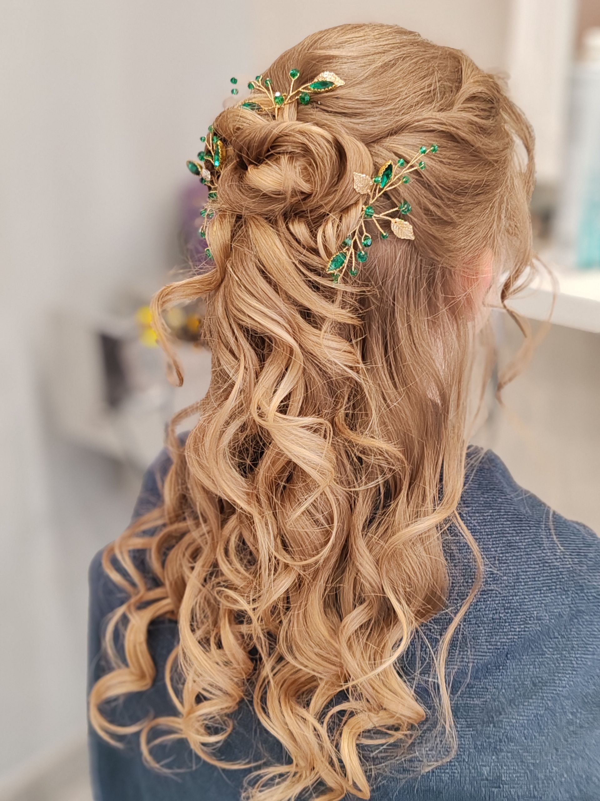Femme aux cheveux blonds ondulés coiffés avec des accessoires pour cheveux verts et dorés.