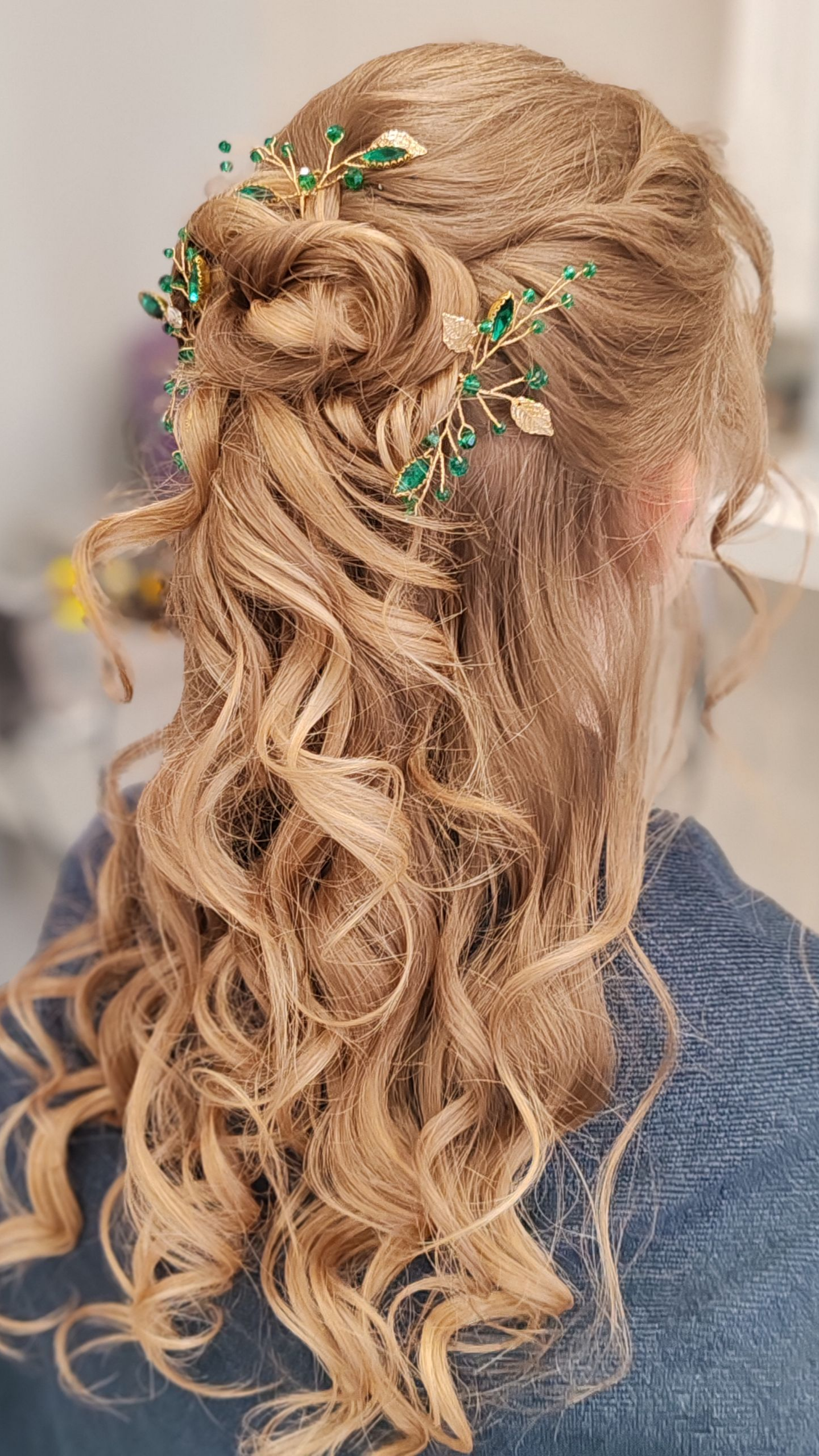 Femme aux cheveux blonds relevés, ornés d'épingles à cheveux vertes et dorées, boucles fluides.