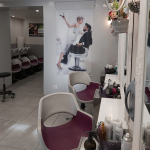 Intérieur de salon de coiffure avec chaises de coiffure, miroirs et une affiche d'un homme et d'une femme.