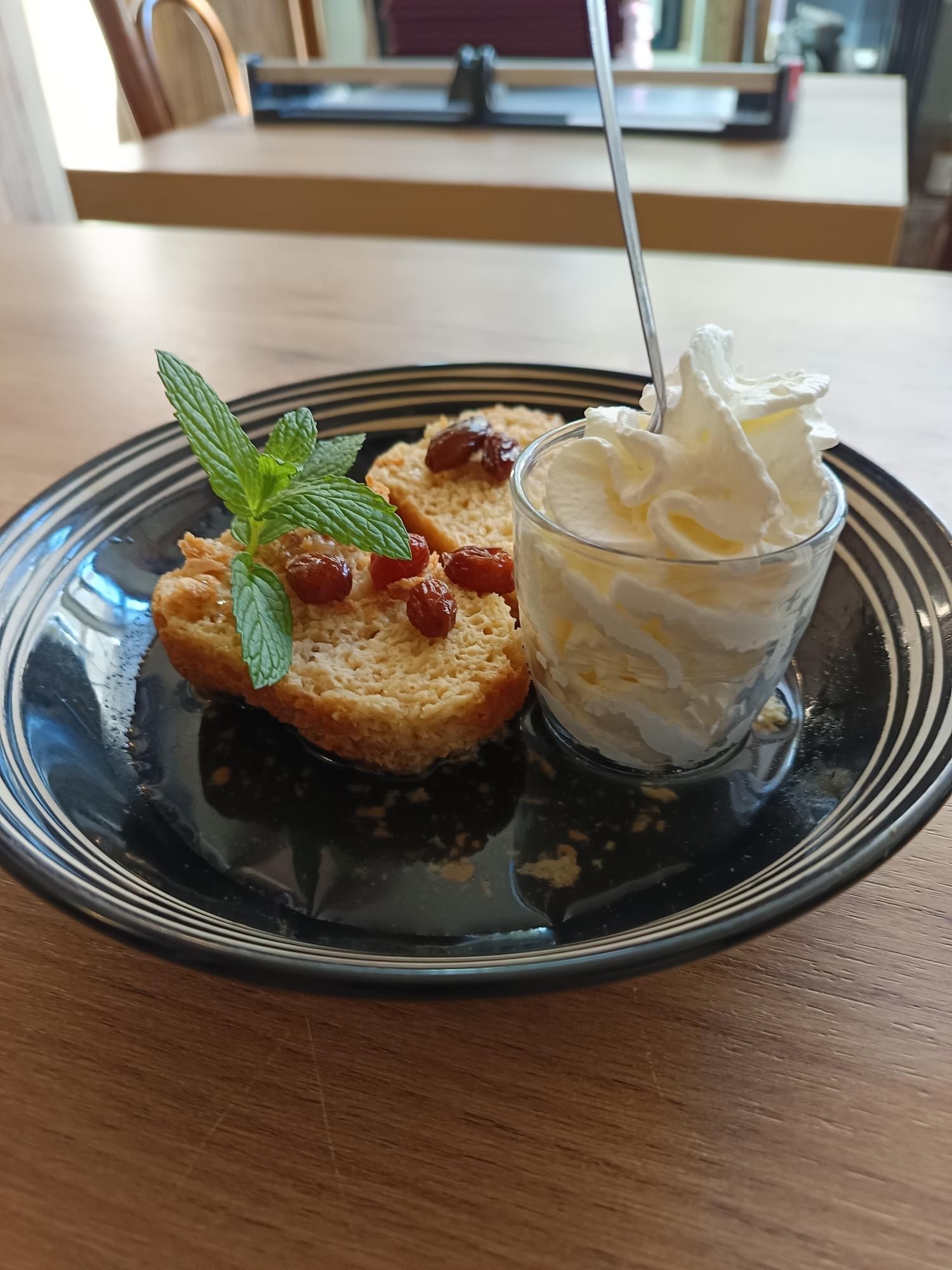 Un petit gâteau moelleux, des raisins secs, de la chantilly sur le côté et quelques feuilles de menthe sur le dessus.
