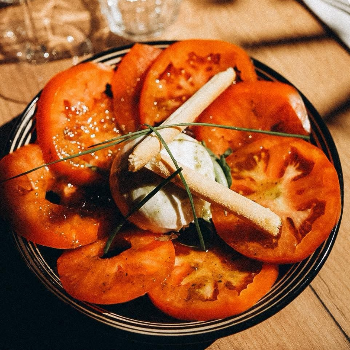 Des rondelles de tomates en cercle avec une burrata au centre.