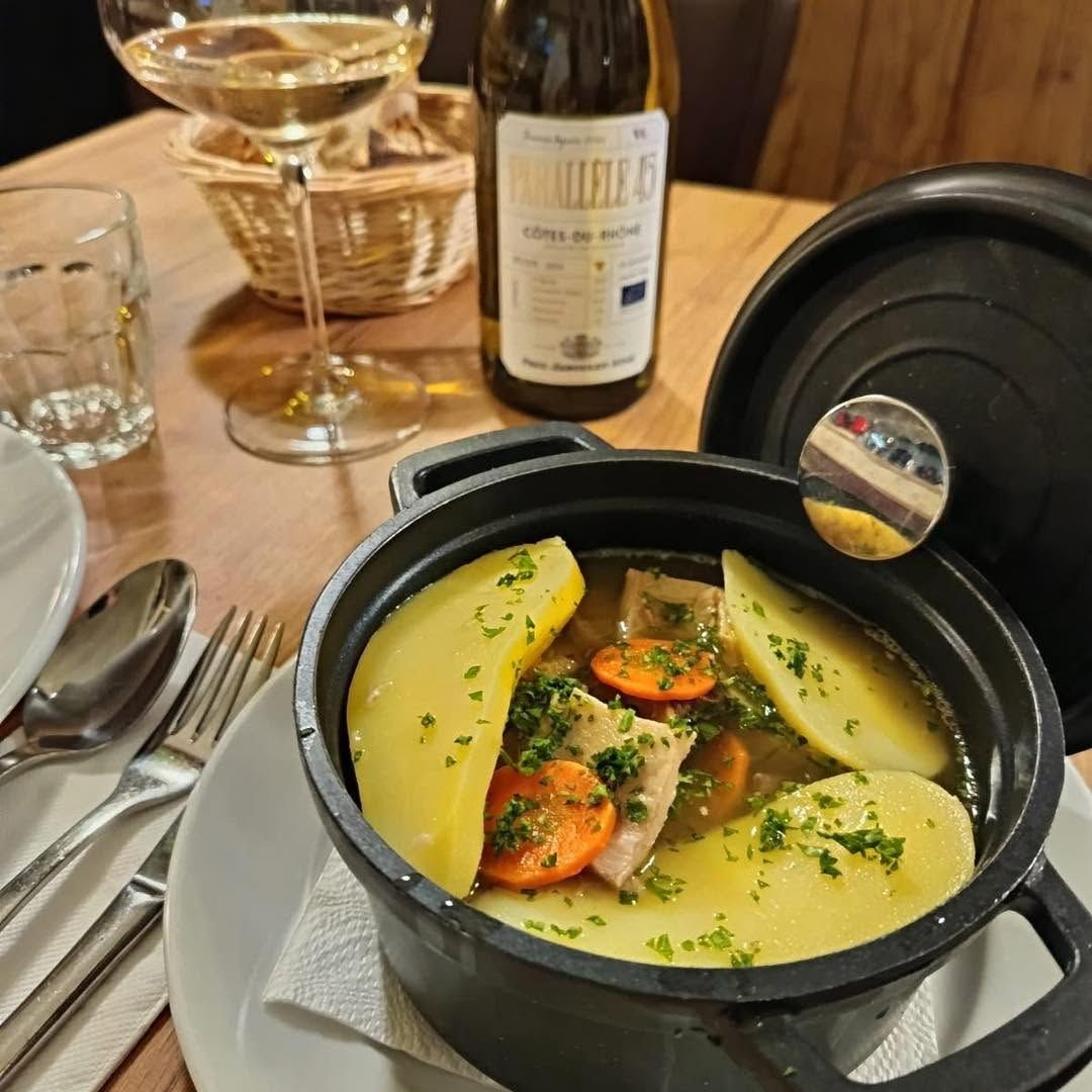 Un plat mijoté dans une petite cocotte avec des pommes de terre, des carottes, de la viande et du bouillon.