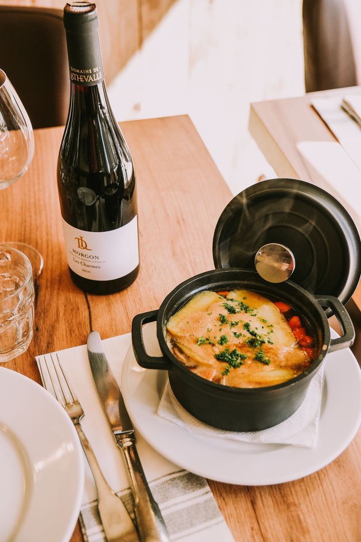 Un plat mijoté avec une bouteille de vin à côté.
