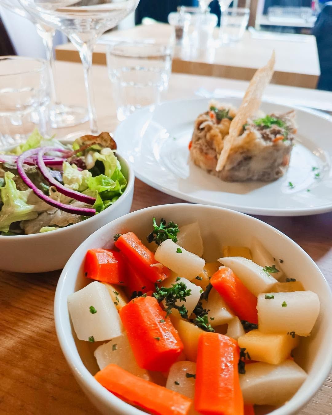 Présentation de trois assiettes avec une terrine, une salade et des légumes persillés.