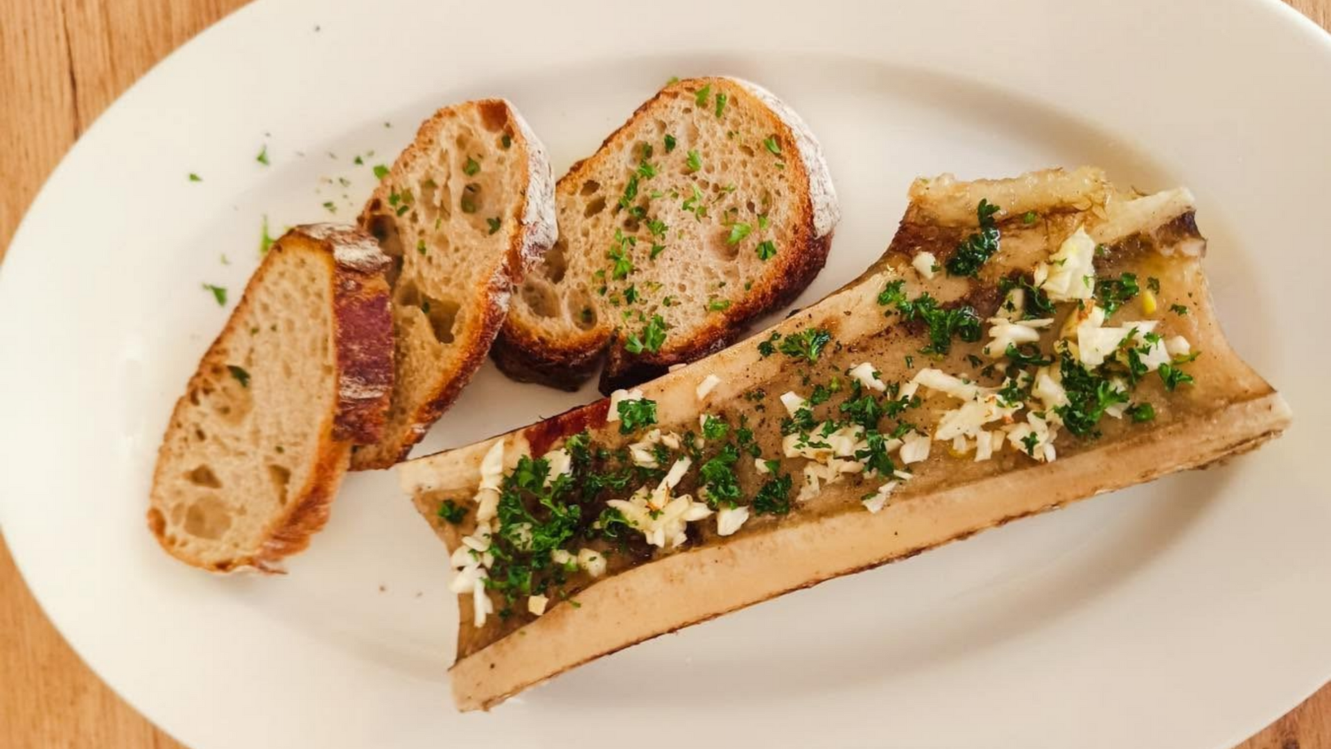 Des tartines de pain dans une assiette avec la moitié d'un os à moelle.