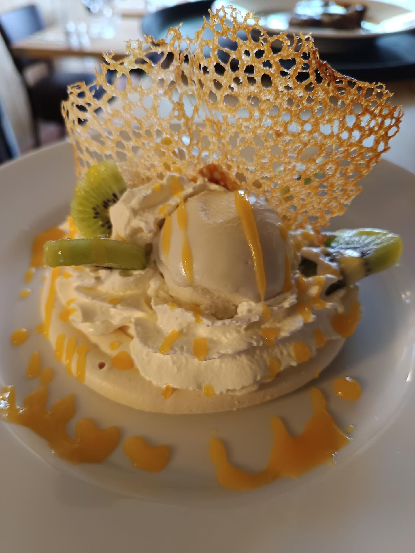 Un dessert avec de la glace à la vanille, des morceaux de fruits et une tuile décorative sur le dessus.