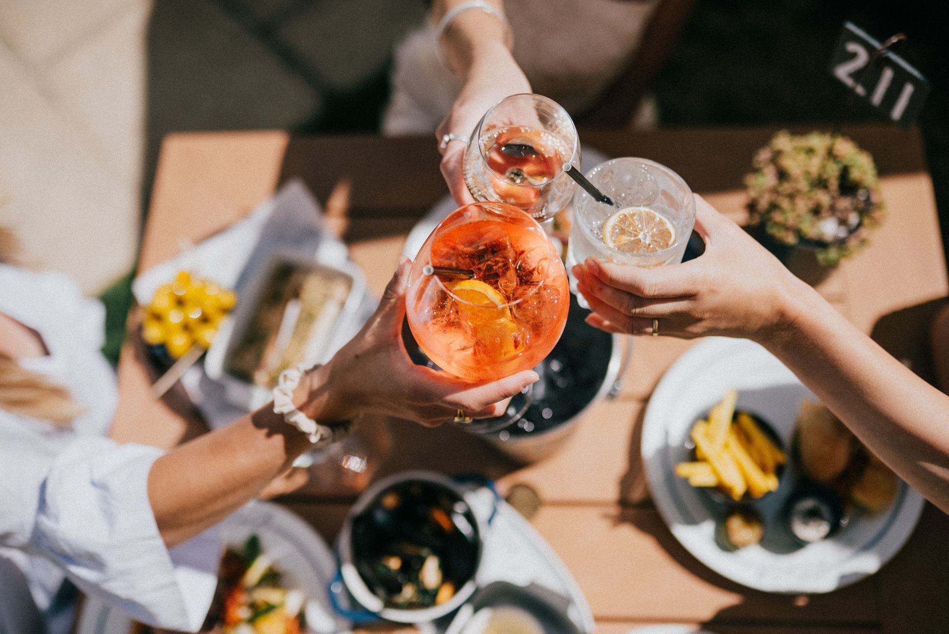 Gros plan sur des verres avec trois personnes qui trinquent.