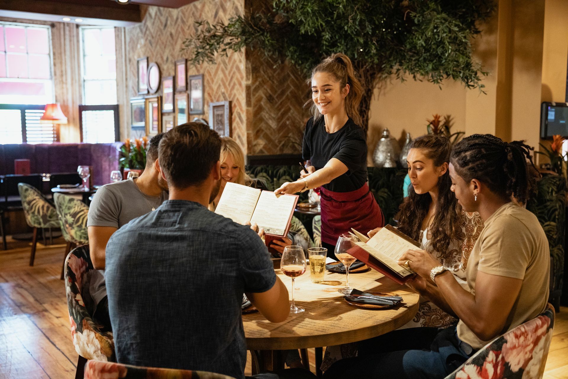 Une serveuse qui tend la carte du restaurant à un client à table.