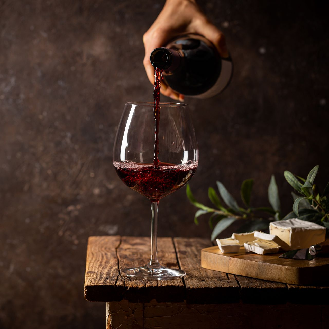 Une personne qui sert un verre de vin rouge.