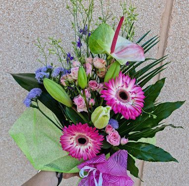 Una persona sostiene un ramo de flores rosas en su mano.